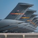 A row of U.S. Air Force military transport aircraft are lined up on a flight line, showing their tail sections in a repeating perspective. The aircraft are marked with 'AETC' (Air Education and Training Command) and 'ALTUS' insignia, indicating they are based at Altus Air Force Base, Oklahoma. Serial numbers visible include 80050 and 44135, consistent with C-17 Globemaster III aircraft.
