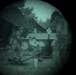 A heavily degraded, circular-vignette image that appears to be viewed through a lens or scope, rendered in a teal/green monochromatic tone. The scene depicts what appears to be an outdoor setting with a tent, trees, a motorcycle or small vehicle, and at least one human figure. The extreme grain, distortion, and circular framing significantly reduce image clarity.