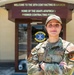 A U.S. Air Force service member stands with arms crossed in front of the 39th Contracting Squadron building. The individual is wearing OCP (Operational Camouflage Pattern) uniform with visible U.S. Air Force tape, a name tape reading 'ELLER', and a 'CONTR' (Contracting) functional badge patch. The building sign identifies it as the home of the USAFE-AFAFRICA Premier Contracting Force.