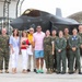 A group of approximately twelve people pose for a photo in front of an F-35 fighter jet on a military airfield tarmac. The group includes both military personnel in Marine Corps camouflage uniforms and flight suits, as well as civilians in casual attire. The setting appears to be a ceremonial or commemorative occasion, possibly a graduation, promotion, or milestone flight event.