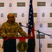 A U.S. Air Force officer is speaking at a podium bearing the Botswana Defence Force seal during what appears to be a bilateral military event. The backdrop features repeated Namibian flags and Botswana Defence Force insignia, while a U.S. flag and Botswana flag are visible on either side of the speaker. The name tape on the uniform reads 'SULLINS' and the uniform includes a U.S. flag patch.