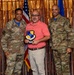 Three individuals pose for a formal award photo at what appears to be a U.S. Air Force recognition ceremony. The center person, dressed in civilian attire, holds a shield-shaped plaque bearing the '72d Air Base Wing' insignia. Two uniformed U.S. Air Force personnel in OCP (Operational Camouflage Pattern) uniforms flank him on either side.