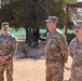 Three U.S. Army soldiers in OCP (Operational Camouflage Pattern) uniforms are standing outdoors in what appears to be a field or training environment. The soldiers are at attention or in a relaxed standing position, possibly receiving a briefing or participating in a formation. Name tapes visible include 'LUCERO' on the right soldier and a partially visible name on the left soldier.