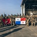A group of armed military personnel pose for a group photograph on an airfield tarmac in front of a large aircraft hangar. Two flags are prominently displayed: a red U.S. Marine Corps flag on the left and the flag of Panama (white with blue and red stars) in the center. This appears to be a joint military exercise or operation between U.S. Marines and Panamanian security forces.