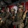 PANAMAX-26: V1/6, Partner forces conduct simulated air raid A group of heavily armed military personnel are seated inside what appears to be a CH-47 Chinook helicopter, equipped with full combat gear. The soldiers are wearing a mix of MARPAT (Marine pattern) and MultiCam camouflage uniforms, suggesting a joint or mixed-unit operation. Several personnel have face paint applied, indicating a tactical or special operations mission context.