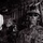 PANAMAX-26: V1/6, Partner forces conduct simulated air raid A black-and-white photograph showing military personnel in full combat gear seated inside what appears to be a military transport helicopter. The foreground soldier is equipped with advanced tactical equipment including a helmet-mounted night vision device, tactical sunglasses, and a plate carrier vest. At least two additional soldiers are visible in the background.