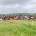 A large group of military personnel from multiple nations pose for a group photograph in an open grassy field with tropical vegetation in the background. Participants are holding several national and military flags, indicating a multinational military exercise or joint training event. The flags visible include those of Mexico, the United States, Panama, Ecuador, and a U.S. Marine Corps flag.