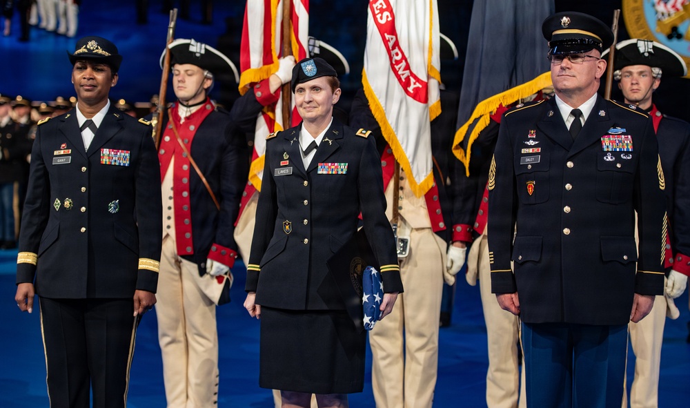 A formal U.S. Army military ceremony featuring three prominent service members standing at the forefront in dress uniforms. Behind them, a color guard in historical Revolutionary War-era uniforms carries flags including a U.S. Army banner. The center figure holds a folded American flag, suggesting a retirement, award, or commemorative ceremony.