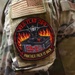 The image shows a close-up of a military uniform sleeve displaying two patches. The upper patch is a subdued American flag, and below it is a circular morale patch for 'Red Flag 26-3' with the motto 'Panther Pack Is Back.' A partial name tape reading 'VALDEZ' (or similar) is visible on the adjacent uniform.
