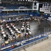 An indoor event is being held on the floor of an ice hockey arena in Fairbanks, Alaska, with the ice removed or covered. The venue appears to be hosting a community or career fair, with numerous tables, chairs, and attendees spread across the arena floor. Signage for 'Alaska Hockey' is prominently visible in the upper right corner of the arena.
