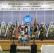 This image depicts the 50th Anniversary Ceremony honoring Major Arthur G. Bonifas and 1st Lieutenant Mark T. Barrett, as indicated by the banner at the top. The ceremony appears to be held at a Joint Security Area (JSA) venue, featuring military honor guards, national flags, and memorial floral wreaths. A memorial photograph of the two officers is displayed on an easel at the center of the stage.