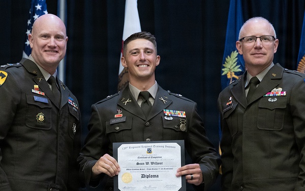 Three U.S. Army soldiers in dress uniforms pose for a formal photograph at a military graduation ceremony. The center individual is holding a diploma/certificate of completion from the 120th Regiment Regional Training Institute issued to Sean W. Wilbour for completing Officer Candidate School. The two flanking individuals appear to be senior officers based on their rank insignia and unit patches.