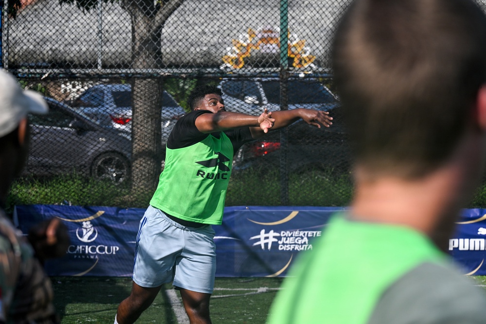 A player wearing a green vest/bib over a black shirt is captured mid-throw or follow-through motion on an outdoor sports court. The event appears to be the 'CAFIC Cup Panama' based on visible sponsorship banners. Puma branding is also visible on a banner in the background.