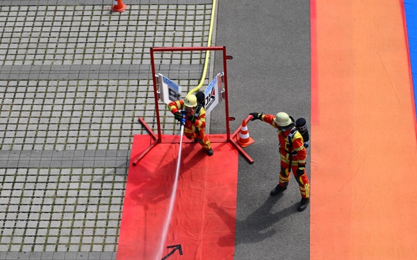 Firefighters conduct hose accuracy drill during competition exercise at outdoor training facility