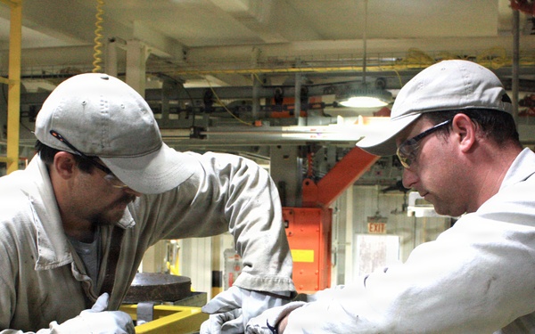 McAlester Army Ammunition Plant employees seal bombs as a part of the production process