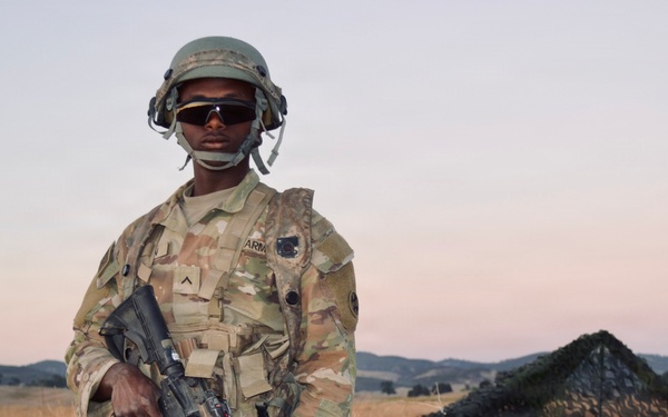 Soldier stands guard at entry control point during CSTX 26 at Fort Hunter‑Liggett