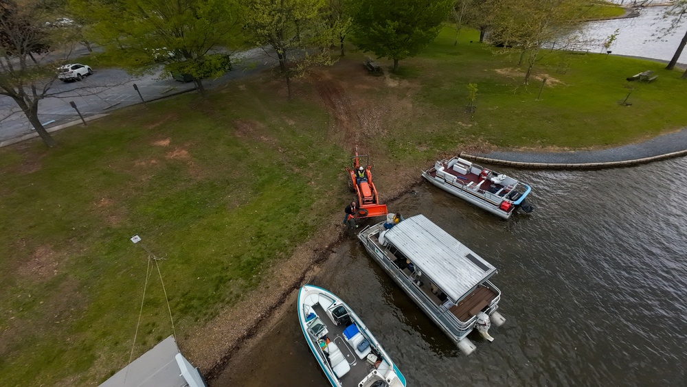Volunteers and U.S. Army Corps of Engineers staff remove debris from the shoreline of Raystown Lake