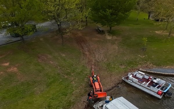 Volunteers and U.S. Army Corps of Engineers staff remove debris from the shoreline of Raystown Lake