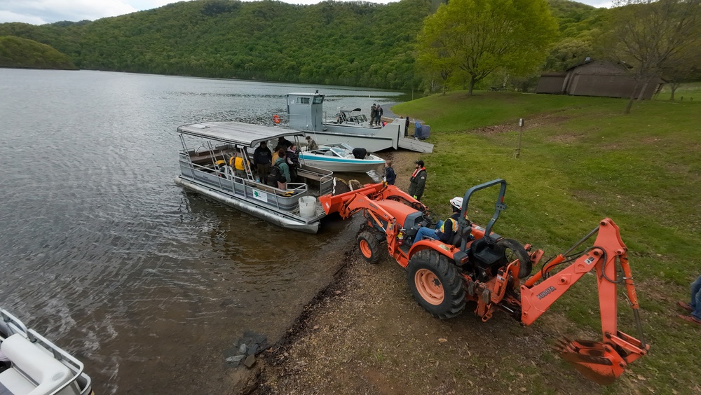 Volunteers and U.S. Army Corps of Engineers staff remove debris from the shoreline of Raystown Lake