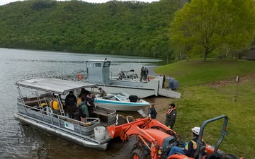 Volunteers and U.S. Army Corps of Engineers staff remove debris from the shoreline of Raystown Lake