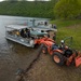 Volunteers and U.S. Army Corps of Engineers staff remove debris from the shoreline of Raystown Lake