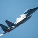 A military jet fighter is captured in a steep climbing maneuver against a blue sky, with afterburners visibly ignited and condensation vapor trails forming over the wings. The aircraft bears the tail number '007' and displays a red insignia patch on the fuselage, consistent with a Republic of Korea Air Force (ROKAF) F-15K Eagle. The image is sharp and well-composed, clearly showing the aircraft's details during a high-performance flight demonstration.