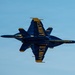 Two U.S. Navy Blue Angels F/A-18 Hornet jets are performing a close formation maneuver, appearing to fly in opposite vertical orientations directly on top of each other. The aircraft are painted in the iconic Blue Angels blue and gold color scheme with 'U.S. NAVY' lettering clearly visible on both fuselages. The image captures a dramatic belly-to-belly or mirror-image pass against a clear blue sky.