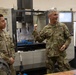 Two U.S. Army soldiers in OCP (Operational Camouflage Pattern) uniforms are standing in what appears to be a machining or fabrication facility. The soldier on the right, identified by name tape as 'LIGHT,' appears to be speaking or explaining something, while the soldier on the left, identified as 'GARCIA,' listens. A CNC milling machine is visible in the background.