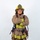 A firefighter in full turnout gear stands in a formal portrait pose with arms crossed against a white studio background. The individual is wearing an ARFF (Aircraft Rescue and Firefighting) helmet marked 'MCAS Miramar' and 'Firefighter,' indicating affiliation with Marine Corps Air Station Miramar. The gear is tan/brown with high-visibility yellow-green reflective striping and includes SCBA harness equipment.