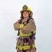 A firefighter in full turnout gear poses against a white background with arms crossed in a confident stance. The helmet displays 'ARFF FIREFIGHTER' and 'MCAS MIRAMAR', identifying this individual as an Aircraft Rescue and Firefighting specialist at Marine Corps Air Station Miramar. The subject is fully equipped with SCBA harness, reflective striping, and firefighting boots.