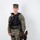 MCAS Marines pose for content 2026 A U.S. Marine in MARPAT woodland digital camouflage uniform stands in a formal portrait pose with a military working dog, likely a Belgian Malinois. The Marine is wearing a tactical vest with a badge, body camera, and other law enforcement equipment, indicating a Military Police or K-9 handler role. The dog is seated beside the handler wearing a black tactical harness.