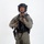 MCAS Marines pose for content 2026 A male individual is photographed against a plain white studio background in full tactical gear. He is wearing olive/sage green combat clothing with a black tactical vest, black ballistic helmet, and is holding a firearm at chest level. The image appears to be a professional equipment or personnel documentation photograph.
