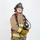 MCAS Marines pose for content 2026 A firefighter in full turnout gear stands against a plain white background in a formal portrait-style photograph. The individual is wearing a black helmet labeled 'ARFF' and 'MCAS Miramar - Lead Firefighter,' indicating affiliation with Aircraft Rescue and Firefighting at Marine Corps Air Station Miramar. The subject holds an SCBA (Self-Contained Breathing Apparatus) face mask and is fully equipped with protective gear.