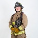 A firefighter in full personal protective equipment (PPE) stands in a formal portrait pose against a white background. The individual is wearing ARFF (Aircraft Rescue and Firefighting) gear from MCAS Miramar, identified as a Lead Firefighter. They are holding a breathing apparatus face mask and have SCBA (Self-Contained Breathing Apparatus) equipment on their back.