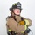 MCAS Marines pose for content 2026 A firefighter in full turnout gear poses against a white background with arms crossed. The helmet identifies them as a 'Lead Firefighter' with 'ARFF' (Aircraft Rescue and Firefighting) designation at 'MCAS Miramar'. The subject is equipped with a Scott SCBA (Self-Contained Breathing Apparatus) tank on their back.