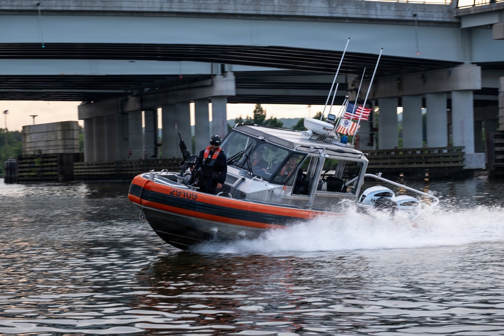 U.S. Coast Guard Response Boat Patrols Waterway Beneath Highway Overpass at Dusk