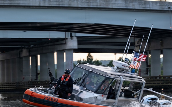 U.S. Coast Guard Response Boat Patrols Waterway Beneath Highway Overpass at Dusk