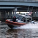 U.S. Coast Guard Response Boat Patrols Waterway Beneath Highway Overpass at Dusk