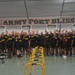 A large group of U.S. Army personnel pose for a group photo inside a fitness facility at Fort Bliss. The individuals are wearing black Army physical training uniforms with 'ARMY' and 'IRON' text, and many are giving thumbs-up gestures. The setting is a well-equipped gymnasium with a prominent 'U.S. ARMY FORT BLISS' banner on the wall behind them.