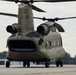 A U.S. Army CH-47 Chinook tandem-rotor helicopter is parked on a tarmac apron, identified by markings 'SC-NG 008779' indicating it belongs to the South Carolina National Guard. The aircraft is viewed from the front-rear quarter angle, showing both rotor systems, twin engines, and an open rear ramp. The rotors appear to be spinning, suggesting the aircraft is running or has recently been operating.