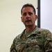 A U.S. Army soldier wearing Operational Camouflage Pattern (OCP) uniform is speaking, likely addressing a group. The name tape reads 'LEWANDOWS' (partially visible, likely Lewandowski) and rank insignia on the collar indicates a senior NCO rank. A Master Parachutist badge is visible on the chest.