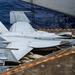 A U.S. Navy F/A-18E/F Super Hornet assigned to VFA-113 (the 'Stingers') is parked on the flight deck of an aircraft carrier, with its wings folded for deck storage. The aircraft bears the modex number 201 and tail code 'NF', indicating assignment to a carrier air wing. A flight deck crew member in a yellow jersey marked 'FLY 3' stands near the aircraft's nose, likely performing a supervisory or directing role.