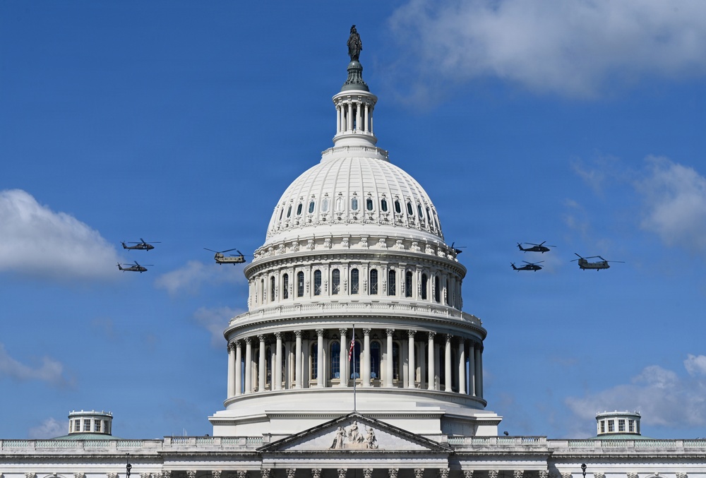 The image shows the United States Capitol Building in Washington, D.C., with its iconic white dome and the Statue of Freedom at its apex. Multiple military helicopters are flying in formation on both sides of the dome against a partly cloudy blue sky. This appears to be a military flyover, likely associated with a ceremonial or national event.