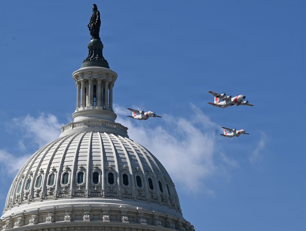 Three U.S. Coast Guard aircraft fly in formation over the dome of the United States Capitol building in Washington, D.C. The aircraft display distinctive white and red Coast Guard livery and appear to be participating in a ceremonial flyover. The Statue of Freedom is visible atop the Capitol dome against a clear blue sky.