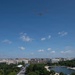 An aerial view of Washington D.C. showing a formation of three military aircraft flying over the National Mall area. The cityscape includes recognizable federal buildings, tree-lined boulevards, and a reflecting pool or water feature visible in the lower right. The scene appears to capture a military flyover event, likely associated with a national celebration or commemoration.