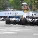 Two IndyCar racing cars are competing side by side on a street circuit, viewed from a rear angle. The cars are approaching a braking zone marked with distance boards (300, 200, 100 meters). The race takes place on a temporary street circuit with concrete barriers, featuring sponsor signage including Starlink and U.S. Border Patrol.