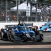 An IndyCar racing event captured on a street circuit, showing multiple open-wheel race cars navigating a turn. The foreground features car number 27 from Andretti Autosport in a blue and black livery with VIZIO and Sonsio sponsorship. A large crowd of spectators is visible behind safety fencing in the background.