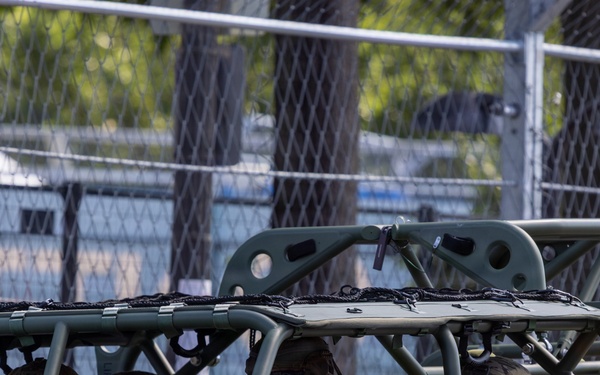 The image shows U.S. Army soldiers seated in a light tactical vehicle, identifiable as an Infantry Squad Vehicle (ISV) based on its olive-drab open-frame roll cage design. The soldiers are wearing MultiCam (OCP) uniforms, combat helmets, sunglasses, and tactical gloves. The vehicle displays markings including 'NON-CARC', 'TIE LVAD', and 'TP 42 PSI', consistent with U.S. Army vehicle labeling standards.