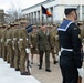 A formal military parade or inspection ceremony is taking place outdoors, likely in Canberra, Australia, based on the distinctive Australian Army slouch hats and the architectural style of the buildings in the background. Two senior officers — one appearing to be a US military officer with a heavily decorated uniform and one an Australian Army officer — are walking along a formed-up honor guard. Multiple branches of the Australian Defence Force are represented, including Army, Navy, and Air Force personnel.