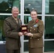 Two senior military officers, one appearing to be a U.S. Marine Corps general and the other an Australian Army officer, pose together while jointly holding a wooden presentation box containing a commemorative coin or medal. The occasion appears to be a formal military exchange or ceremony, likely involving a gift presentation between allied forces. Both officers are in dress uniforms displaying numerous medals and insignia indicating high rank.
